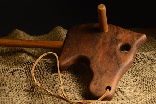 A closeup of an antique wooden horse toy over some brown burlap fabric.