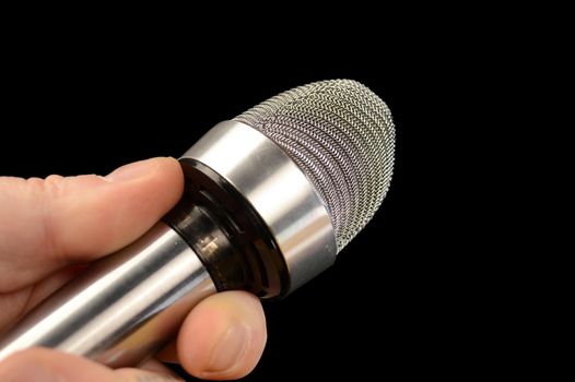 An interviewing reporter using his microphone over a black background.