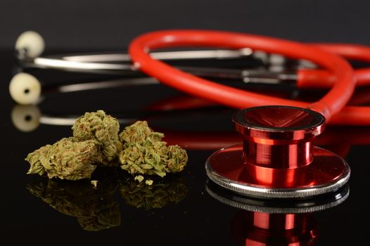 A closeup of some medical marijuana buds next to a red stethoscope for various healthcare concepts.