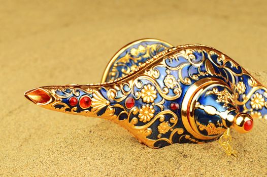 A legendary discovery of a magical Genie lamp shown slightly revealed in the sands over time.