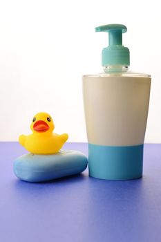 A bar of soap and liquid dispenser over a blue background remind us to wash our hands with a fresh clean feeling.
