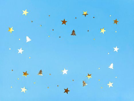 Confetti stars and trees sparkling on a blue background.