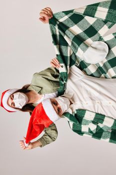 Happy men and women in New Year's hats and in a medical mask on a beige background. High quality photo