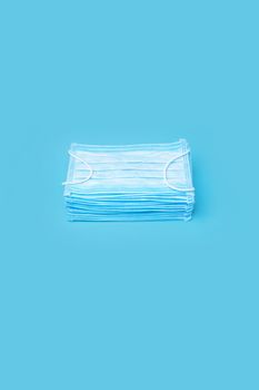 Medical Masks for Protection against Coronavirus Pandemic, Covid-19. Disposable Masks on Blue Background. Typical 3-ply Surgical Mask Stacked Pile. Stack Mask. Pile Mask. Many Blue Medical Face Masks