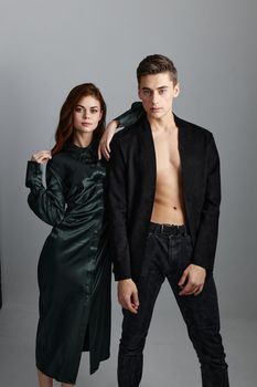 A sexy man in trousers and a jacket stands next to a beautiful woman. High quality photo