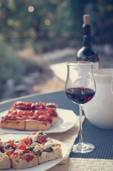 Italian Dinner with red wine, pizza and bread outside. Vacation