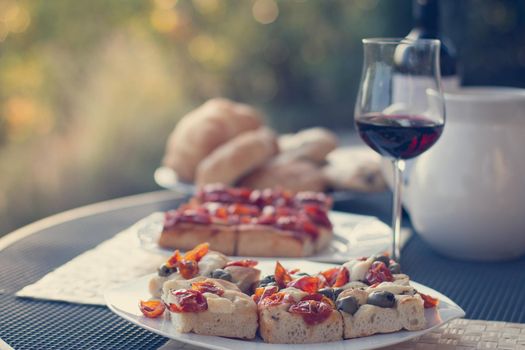 Italian Dinner with red wine, pizza and bread outside. Vacation
