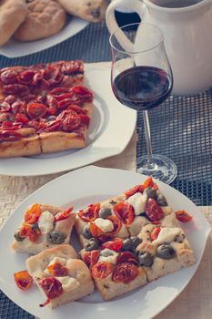 Italian Dinner with red wine, pizza and bread outside. Vacation