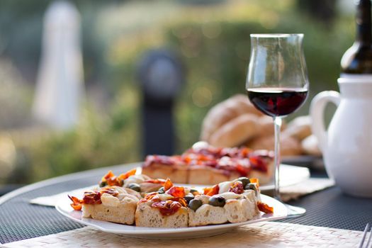 Italian Dinner with red wine, pizza and bread outside. Vacation