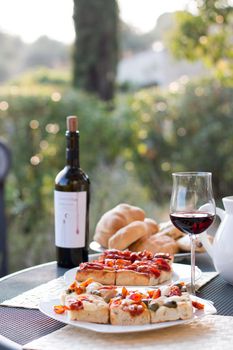 Italian Dinner with red wine, pizza and bread outside. Vacation