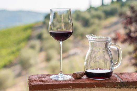 Enjoying a glass of red wine at Tuscany, Italy. Blurry wine yards in the background.