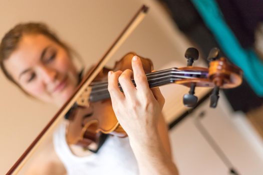 Pretty young girl practices on her violin, acoustic music