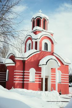 Beautiful snowed red church in the winter, blue sky