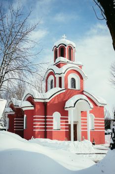 Beautiful snowed red church in the winter, blue sky