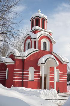 Beautiful snowed red church in the winter, blue sky