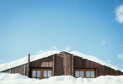 Modern wood house in the winter: Snow on the roof, blue sky