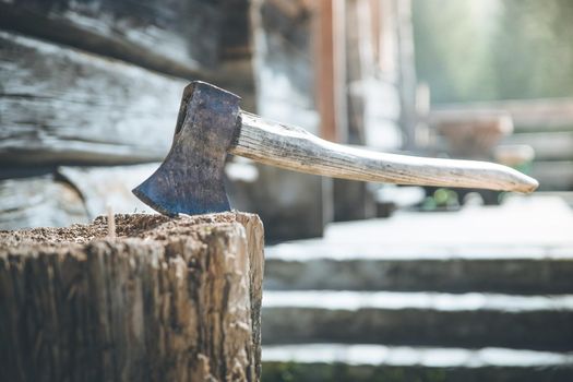 Old axe attached to a tree trunk, alpine hut