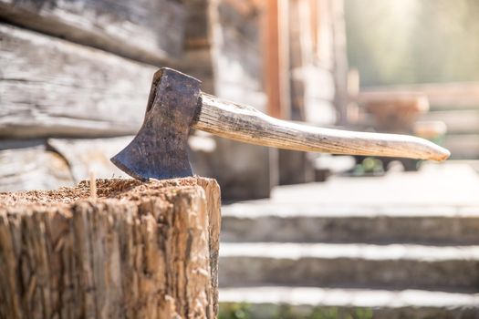 Old axe attached to a tree trunk, alpine hut