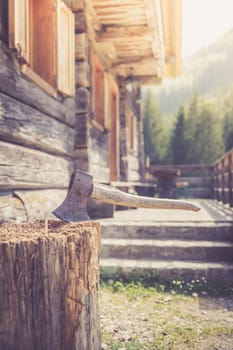 Old axe attached to a tree trunk, alpine hut