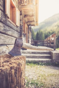 Old axe attached to a tree trunk, alpine hut