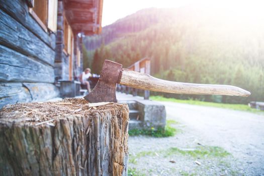 Old axe attached to a tree trunk, alpine hut