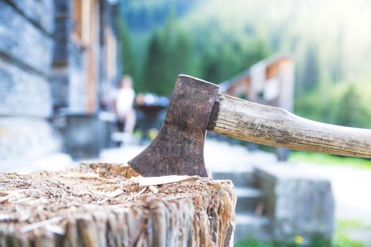 Old axe attached to a tree trunk, alpine hut