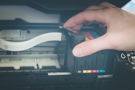 Putting new printer cartridge into the printer, inkjet.
