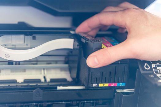 Putting new printer cartridge into the printer, inkjet.