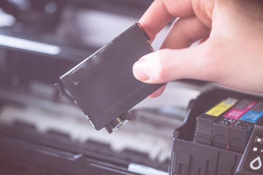 Putting new printer cartridge into the printer, inkjet.