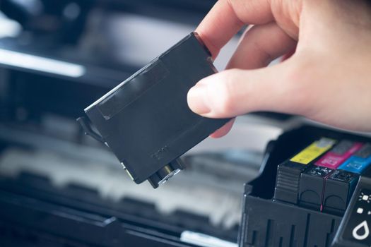 Putting new printer cartridge into the printer, inkjet.