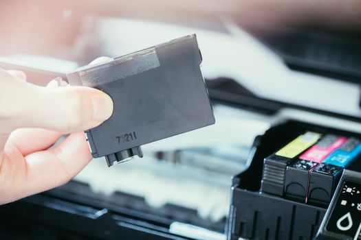 Putting new printer cartridge into the printer, inkjet.