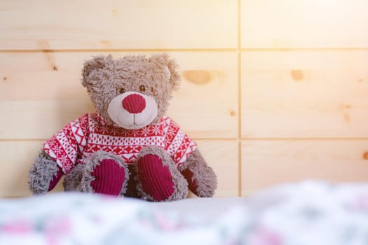 Cute teddy bear toy is sitting in the bed, wakeup at morning, sunlight