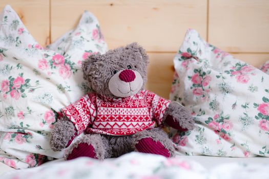 Cute teddy bear toy is sitting in the bed, wakeup at morning