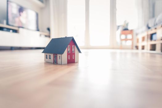 Red house model on the floor, indoors. Concept for new home, property and estate