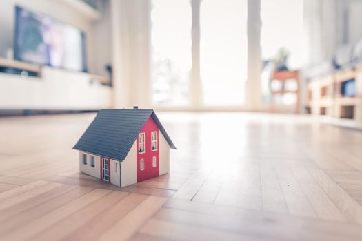 Red house model on the floor, indoors. Concept for new home, property and estate