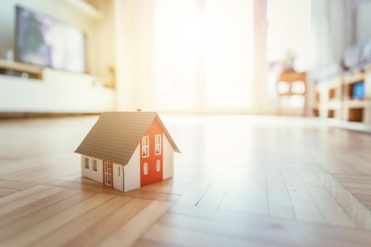 Red house model on the floor, indoors. Concept for new home, property and estate