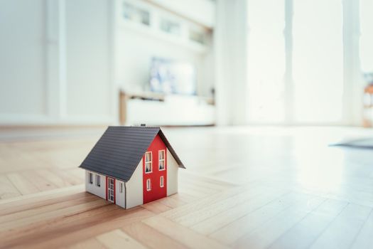 Red house model on the floor, indoors. Concept for new home, property and estate