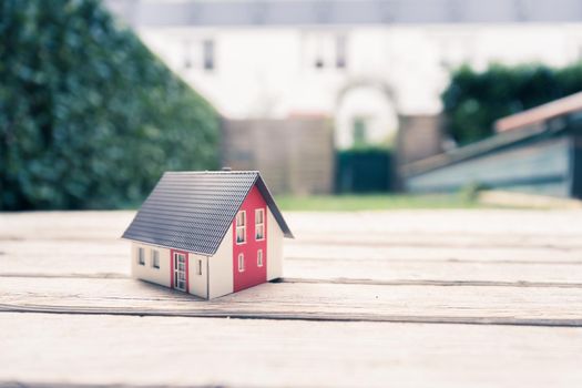 Red house model on the floor, outdoors. Concept for new home, property and estate