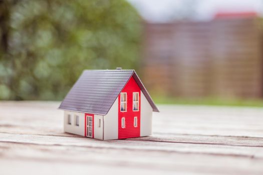 Red house model on the floor, outdoors. Concept for new home, property and estate