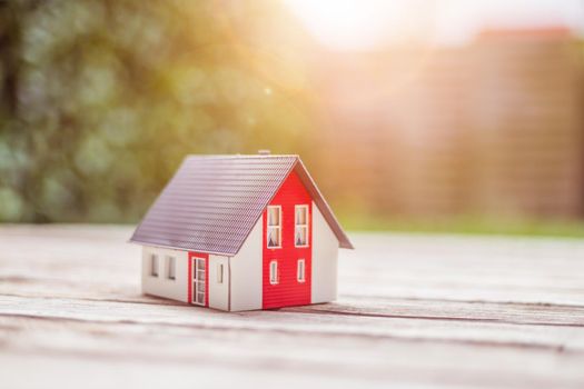 Red house model on the floor, outdoors. Concept for new home, property and estate
