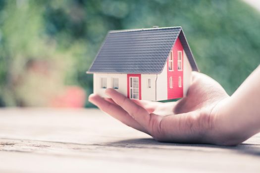 New home and house concept: Red house model outdoors in male hand