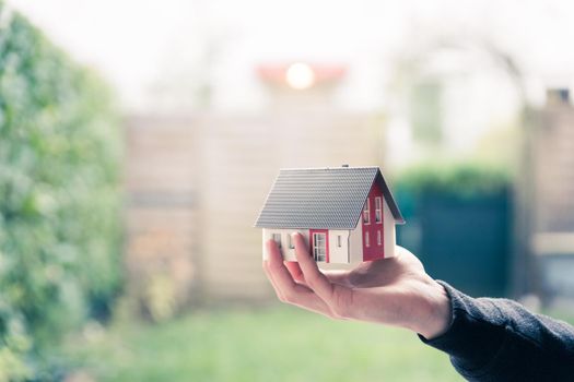 New home and house concept: Red house model outdoors in male hand