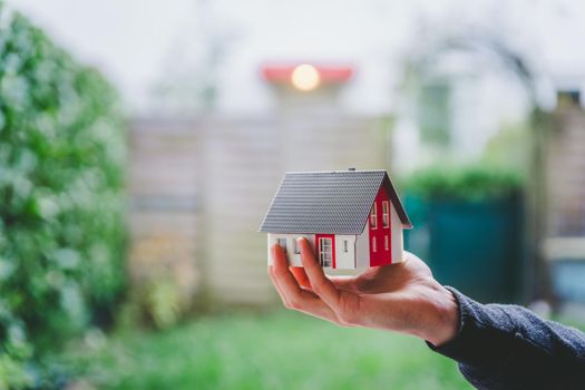 New home and house concept: Red house model outdoors in male hand