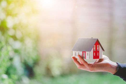 New home and house concept: Red house model outdoors in male hand, copy space