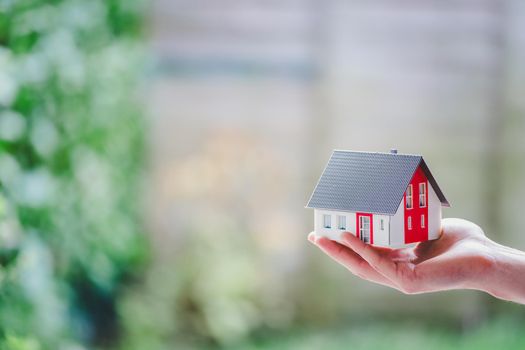 New home and house concept: Red house model outdoors in male hand