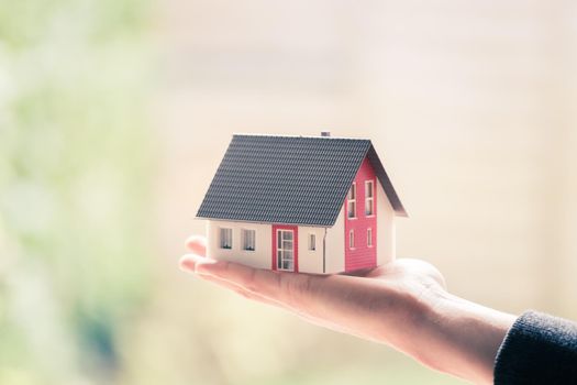 New home and house concept: Red house model outdoors in male hand