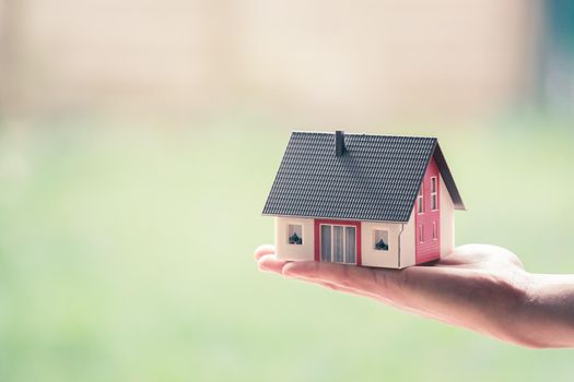 New home and house concept: Red house model outdoors in male hand