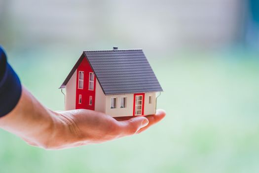 New home and house concept: Red house model outdoors in male hand