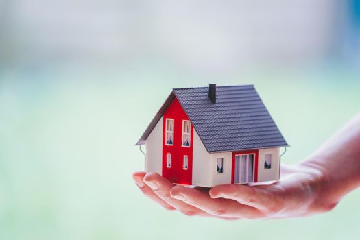 New home and house concept: Red house model outdoors in male hand