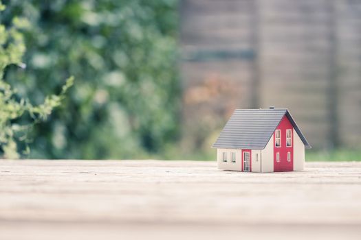 Red house model on the floor, outdoors. Concept for new home, property and estate, copy space